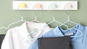 Child's school uniform on coat hangers hanging on colourful hooks
